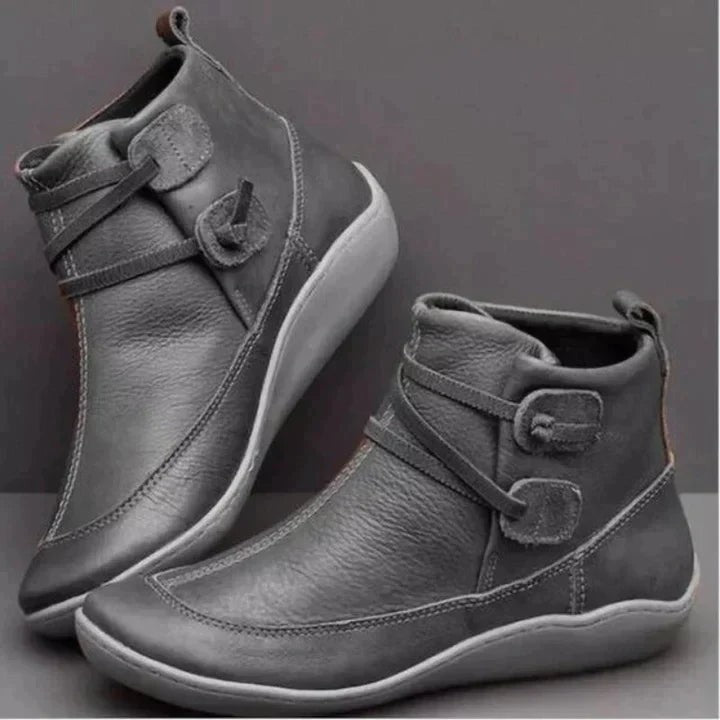Grey leather ankle boots showing buckle straps and durable flat wedge sole