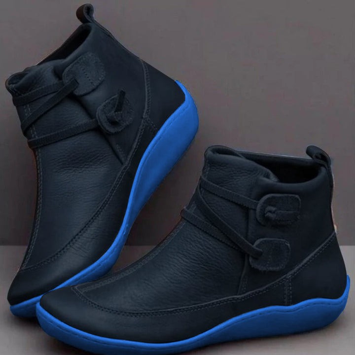 Black leather ankle boots with striking blue sole and buckle strap detailing
