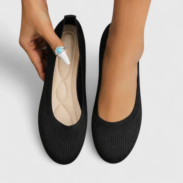 Black knit ballet flats worn on feet with quilted insole detail