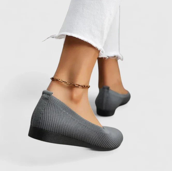 Gray knit ballet flats worn on feet showing back heel design