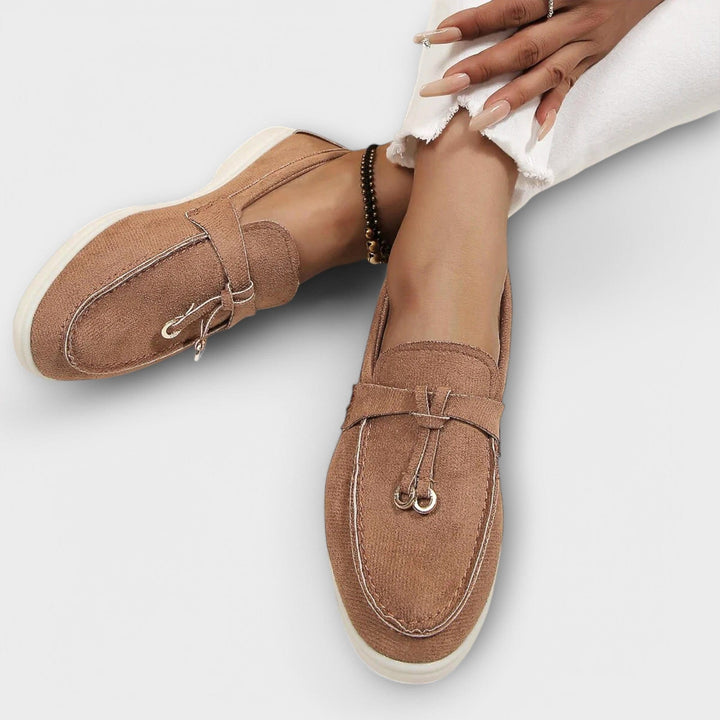 Tan suede loafers with tassel accents worn with cropped white pants