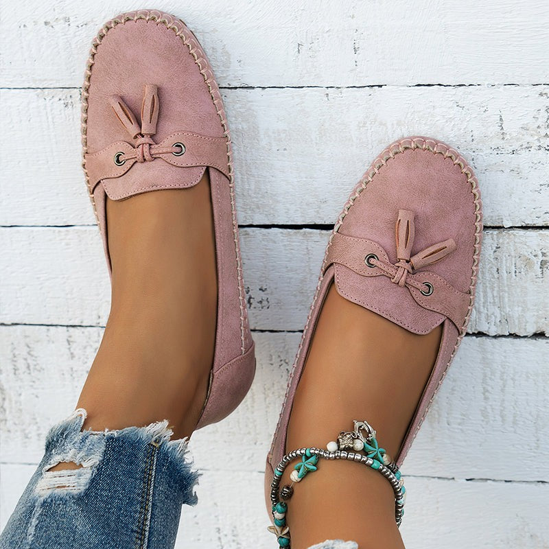 Pink suede tassel loafers with scalloped stitching viewed from above