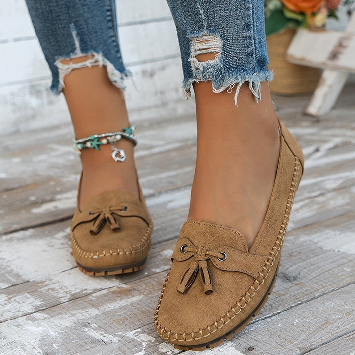 Camel brown suede tassel loafers shown on foot with distressed denim