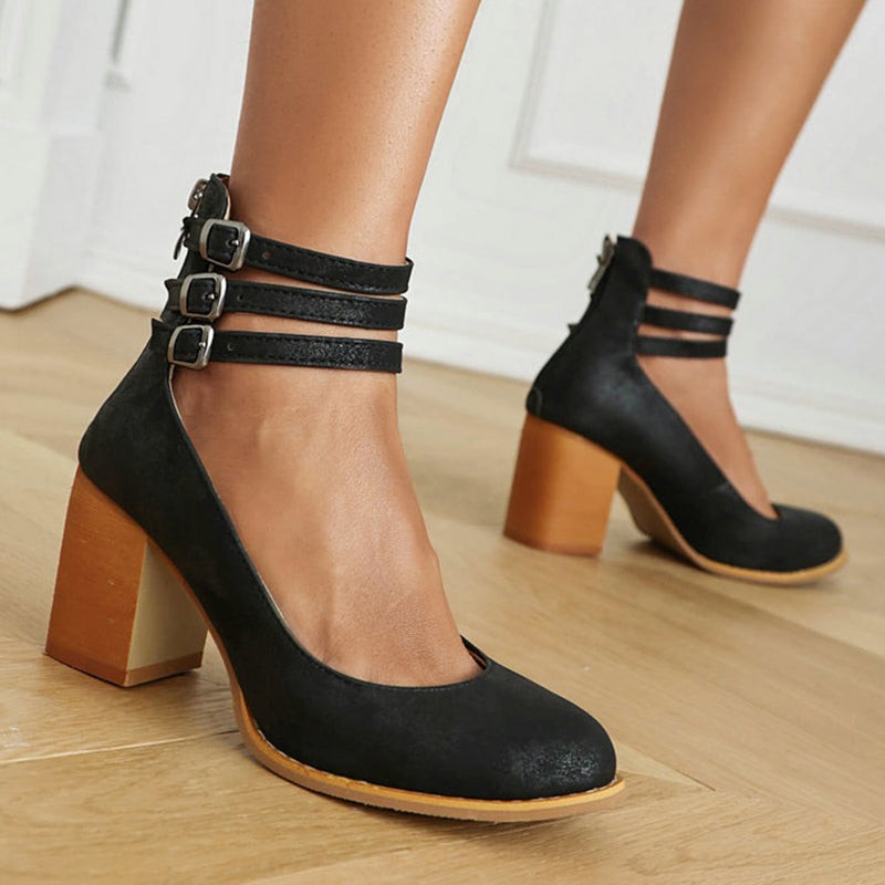 Black suede ankle-strap pumps with triple buckle straps and wood-tone block heel