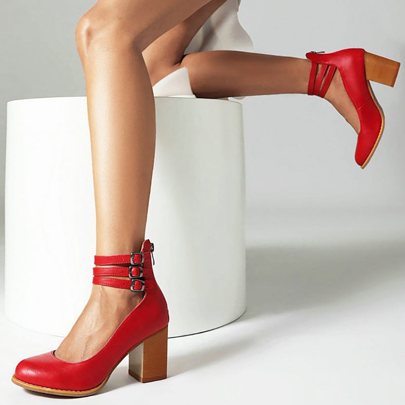 Red leather block-heel pumps with triple ankle straps, seated pose