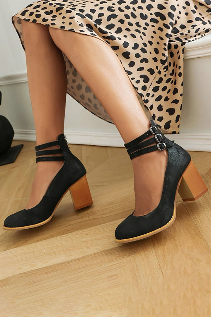 Black suede block-heel pumps with triple ankle straps, styled with leopard print dress