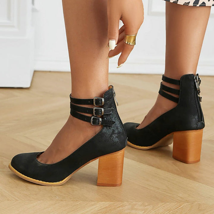Black suede block-heel pumps with triple buckle ankle straps and zipper back
