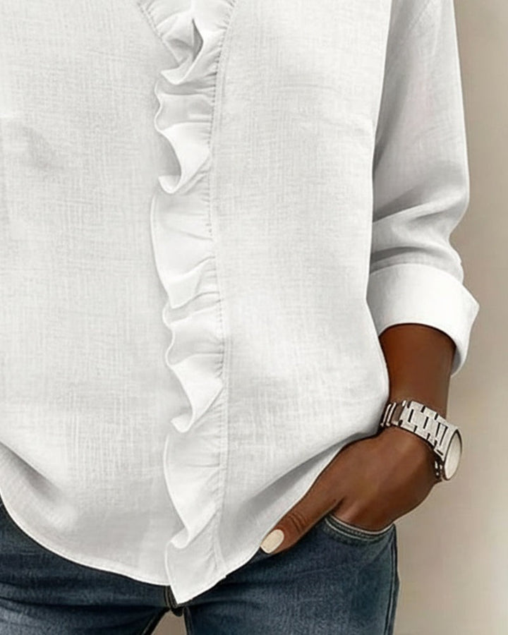 White blouse close-up highlighting ruffle trim and cuffed sleeve