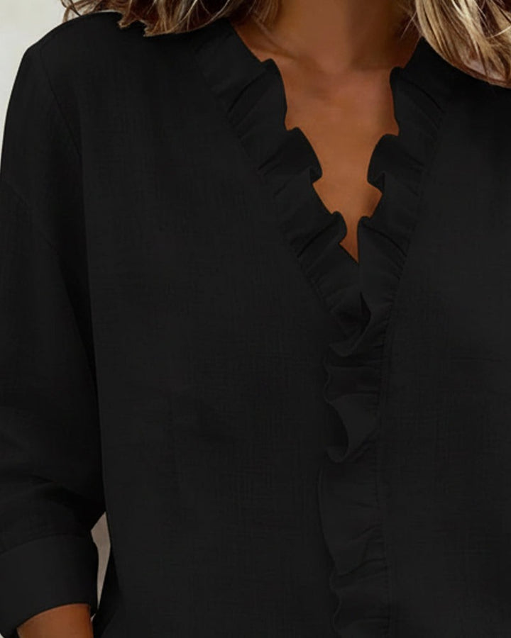 Black blouse ruffled V-neckline shown in close-up detail
