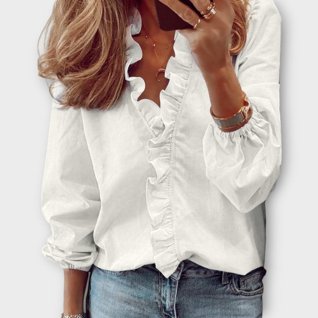 White ruffle-trim blouse with V-neck and long puff sleeves, paired with jeans