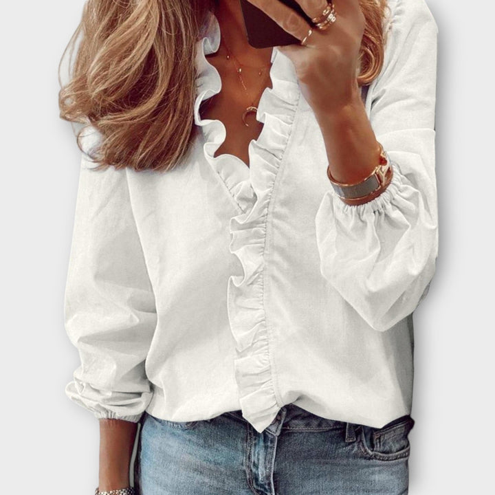 White ruffle-trim blouse with V-neck and long puff sleeves, paired with jeans