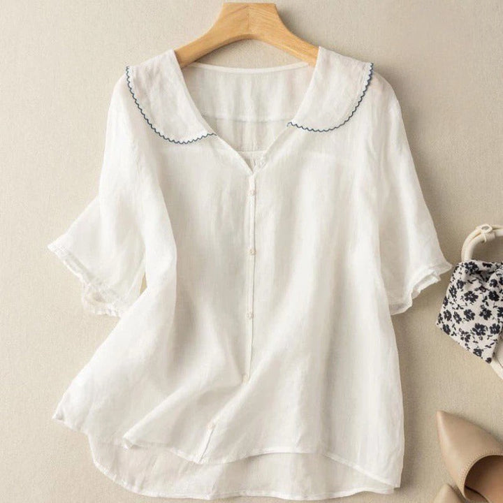 White linen blouse with navy scalloped trim collar and short ruffled sleeves