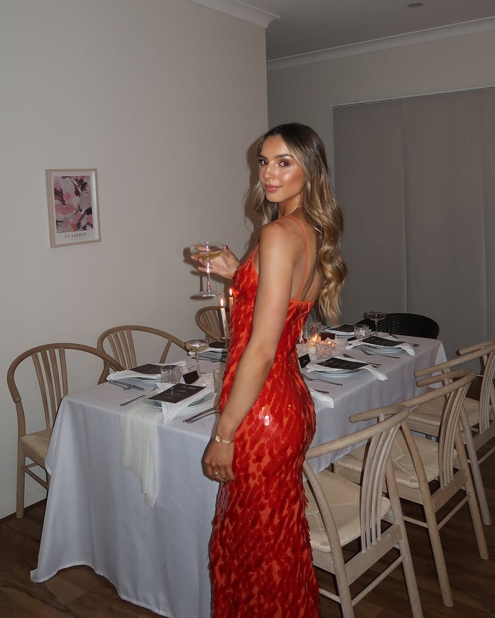 backless red sequin gown paired with champagne glass at formal dinner