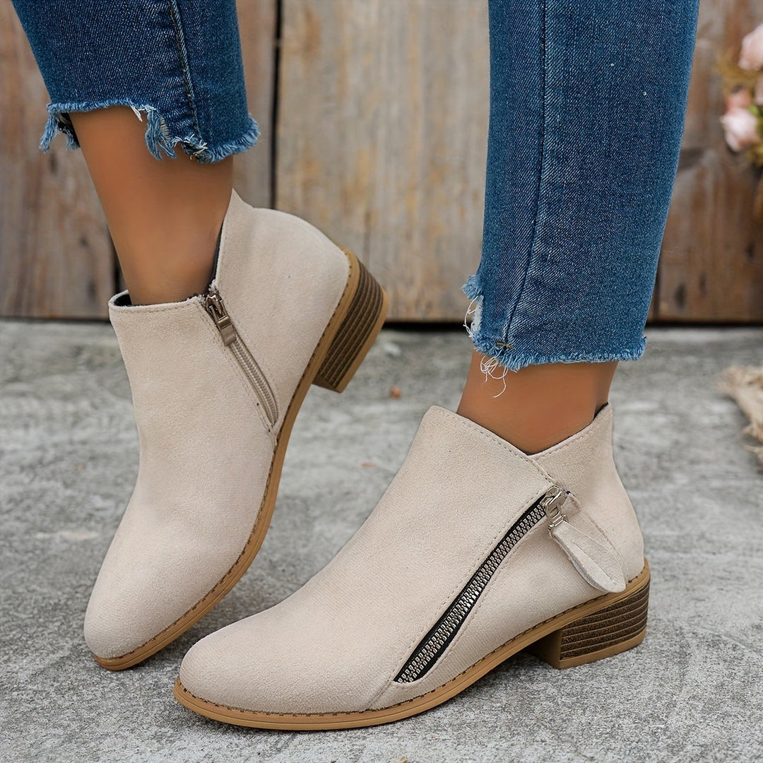 Beige suede ankle boots with pointed toe worn with ripped jeans