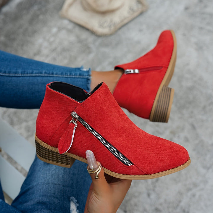 Red suede ankle boots with side zip fastening held in hand
