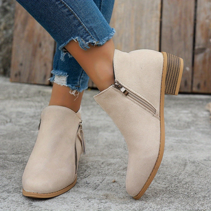 Beige suede ankle boots with decorative zip detail worn on model