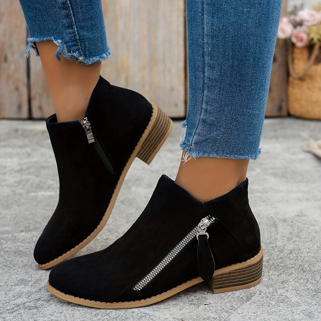 Black suede ankle boots worn on model with cropped denim jeans