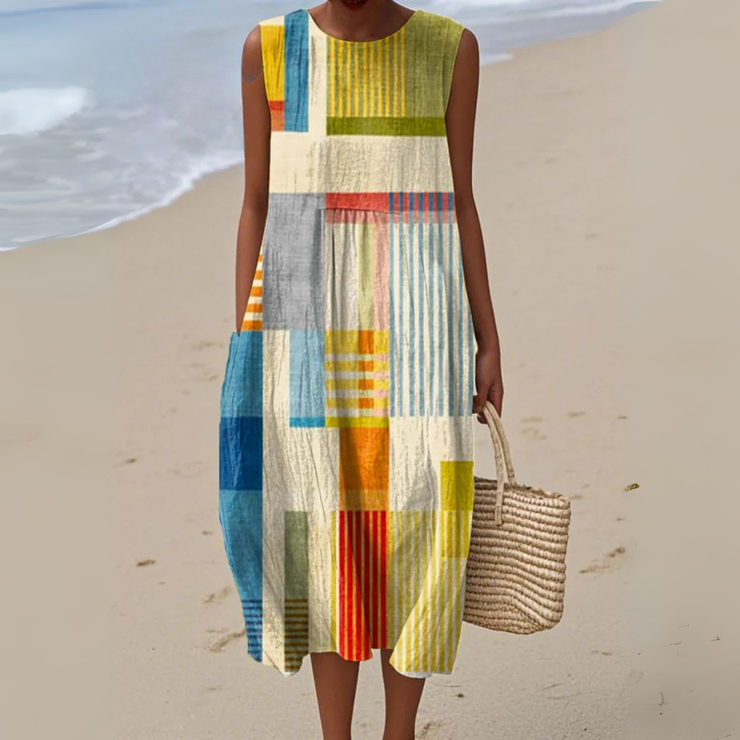 Sleeveless midi dress with colorful geometric patchwork print, worn at the beach