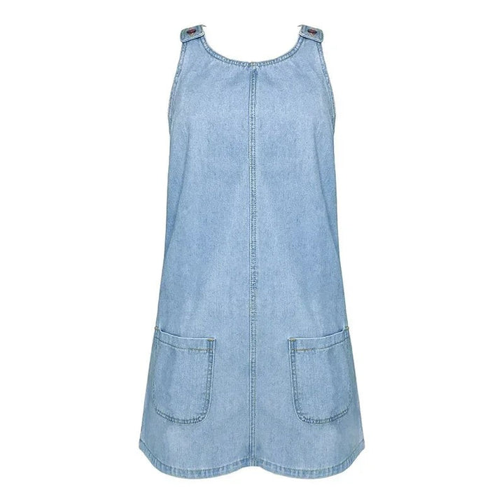 Light wash denim overall dress with patch pockets on plain background