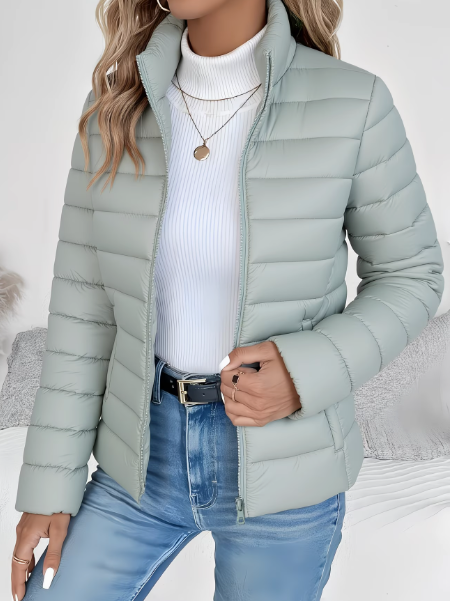 Sage green quilted puffer jacket with stand collar worn over white sweater