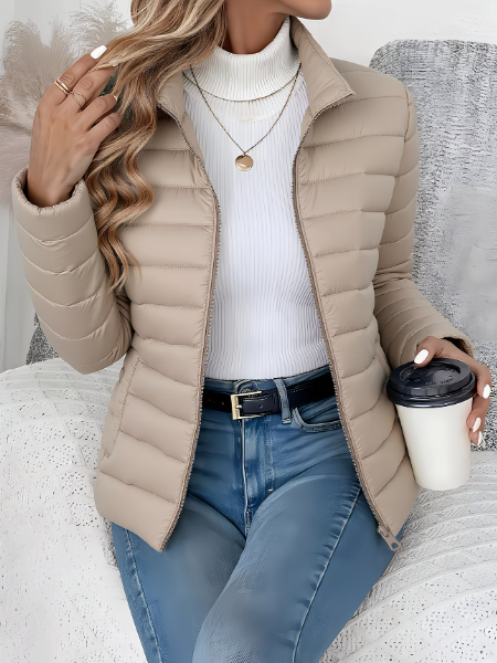 Beige quilted puffer jacket paired with white turtleneck and layered necklaces