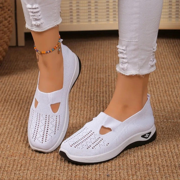 White knit slip-on sneakers with cutout detail worn on woven rug