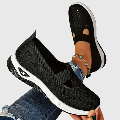 Black knit slip-on shoe shown from side angle with white wedge sole