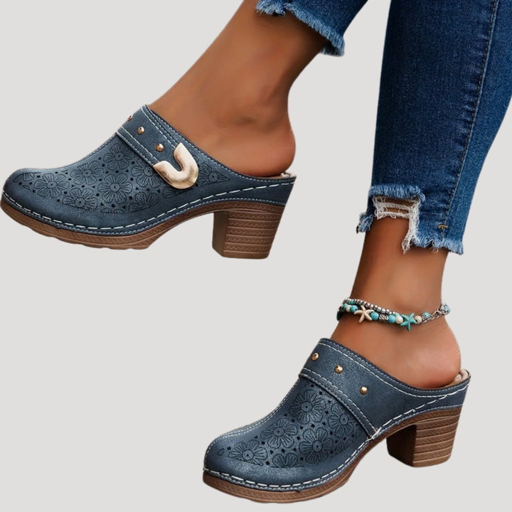 Blue leather clog mules showing perforated flowers and chunky wooden heel