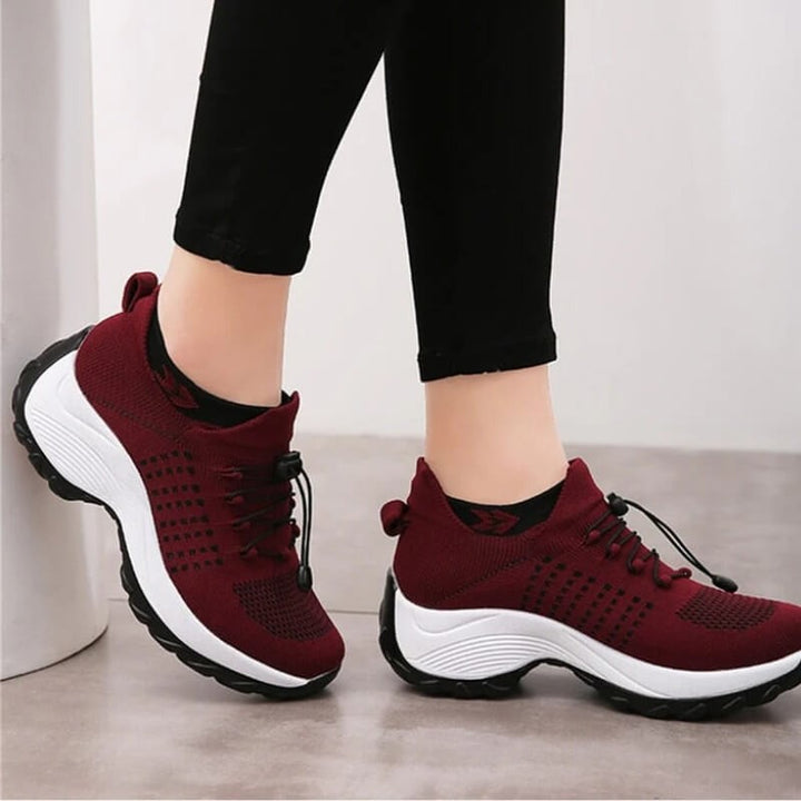 burgundy platform sneakers worn on feet paired with black cropped pants