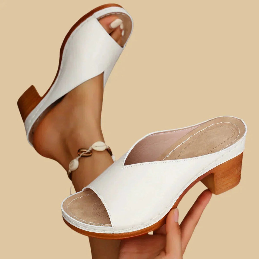 white peep-toe mule sandals with contrast stitching and wood-tone heel