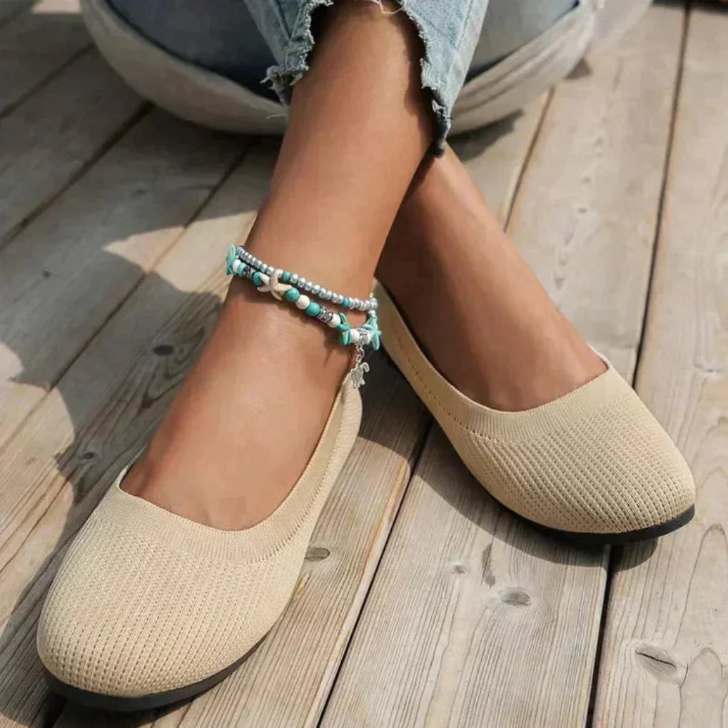 Beige knit slip-on flats paired with ripped jeans on wooden deck