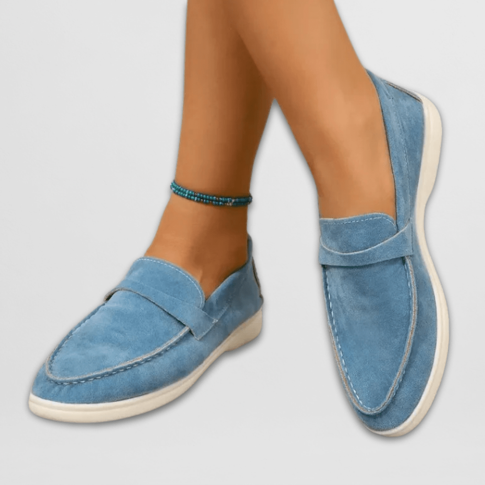 Sky blue suede penny loafers featuring white stitched trim and flat sole