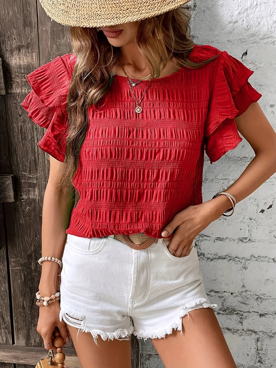 Red ruffle-sleeve smocked top styled with white shorts and straw hat