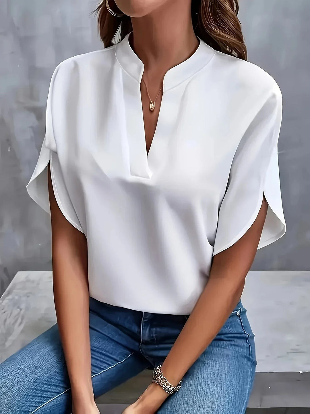 White split-sleeve blouse featuring notched V-neck and relaxed batwing fit