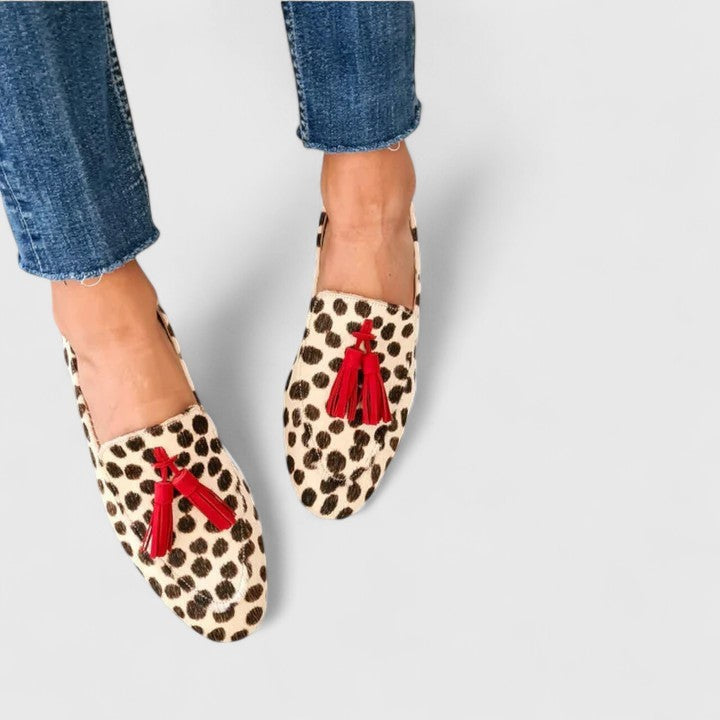 Leopard print orthopedic loafers with red tassel accents, worn with jeans