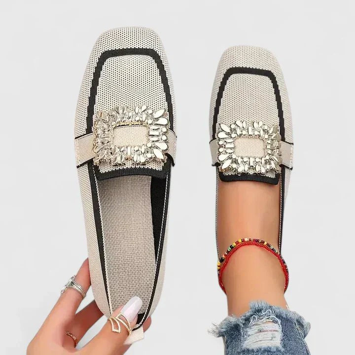 Beige knit flats with black trim and crystal buckle embellishment