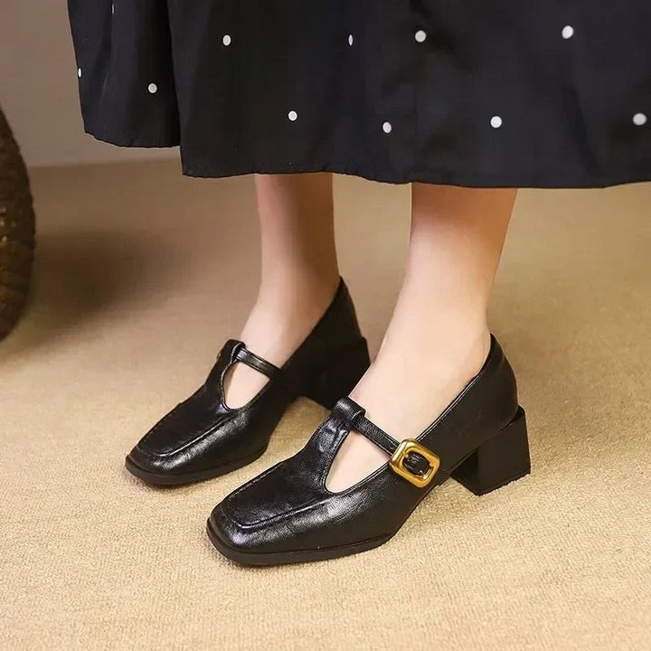 Black leather Mary Jane heels featuring T-strap and gold buckle accent