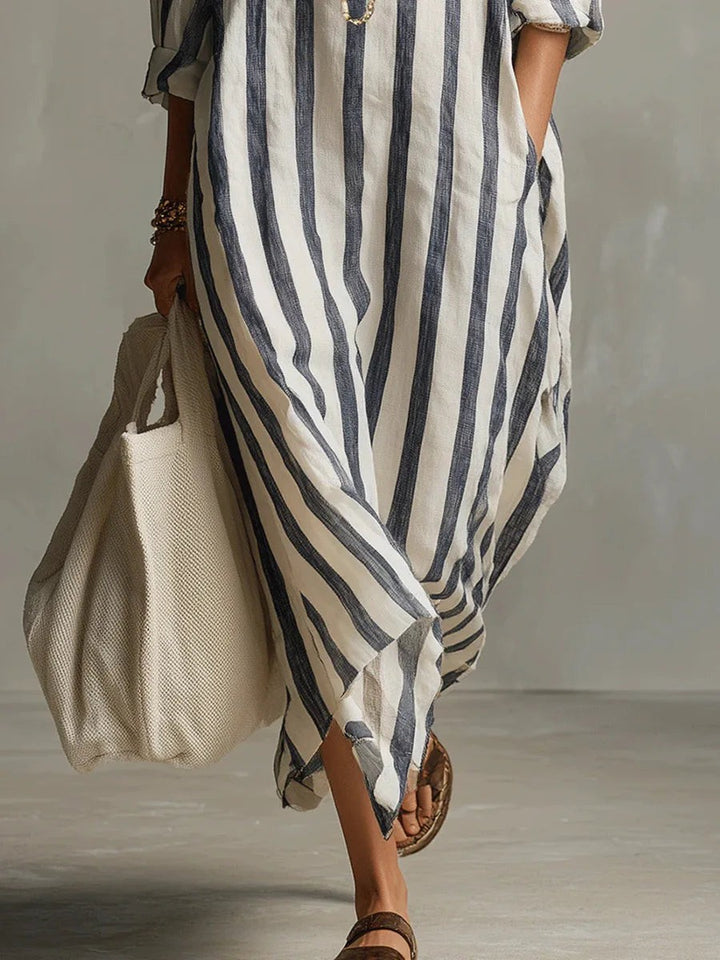 Flowing hemline detail of striped linen maxi dress with rolled sleeves