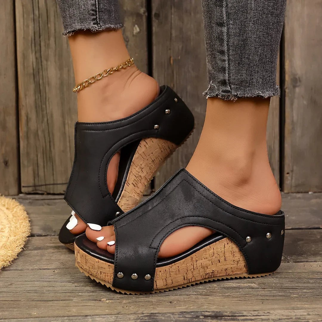 Black studded peep-toe cork wedge sandals worn with cropped denim jeans