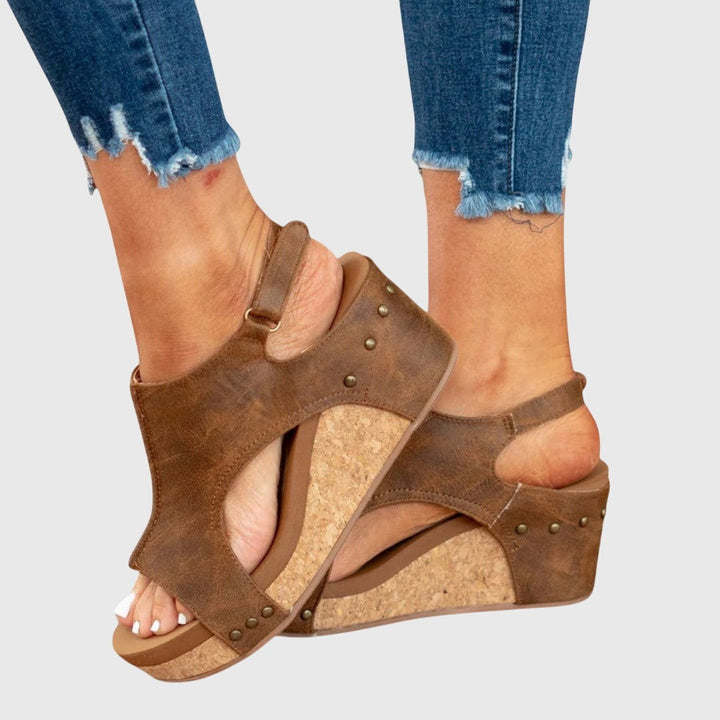 Side angle of brown wedge sandal showing cork platform and studs
