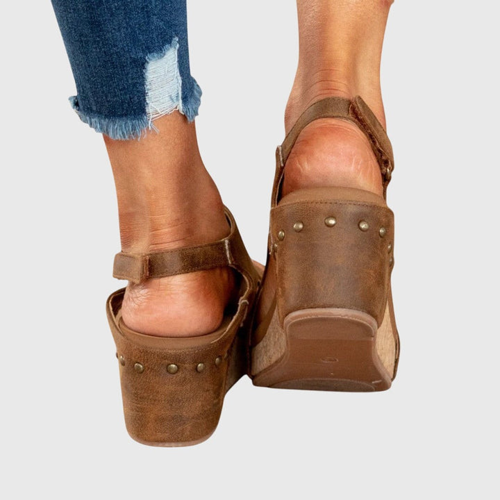 Brown wedge sandal heel view with studded trim and cork platform sole