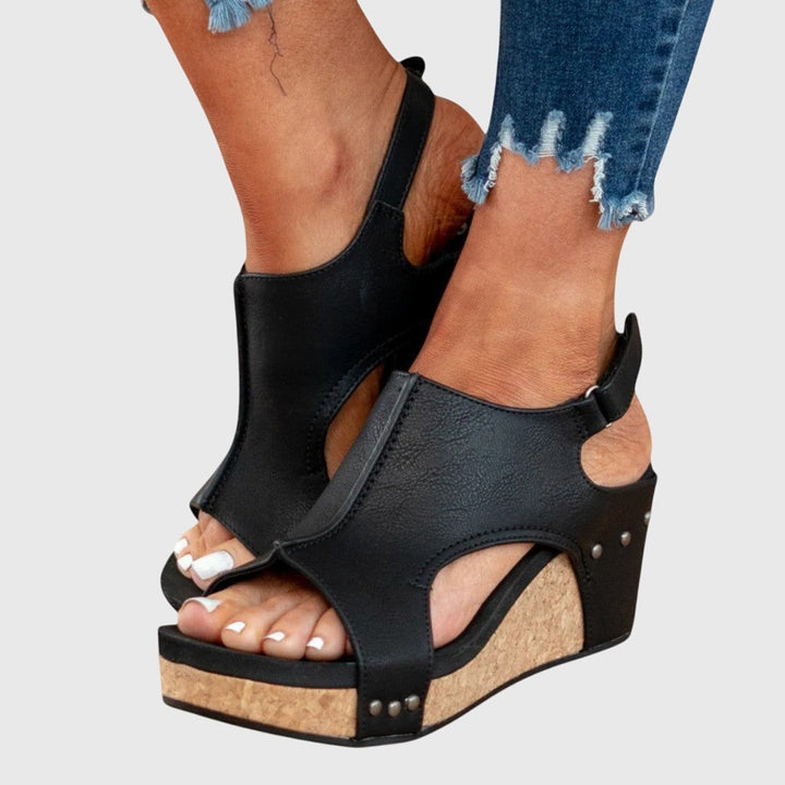 Studded black wedge sandals featuring cutout sides and cork platform heel