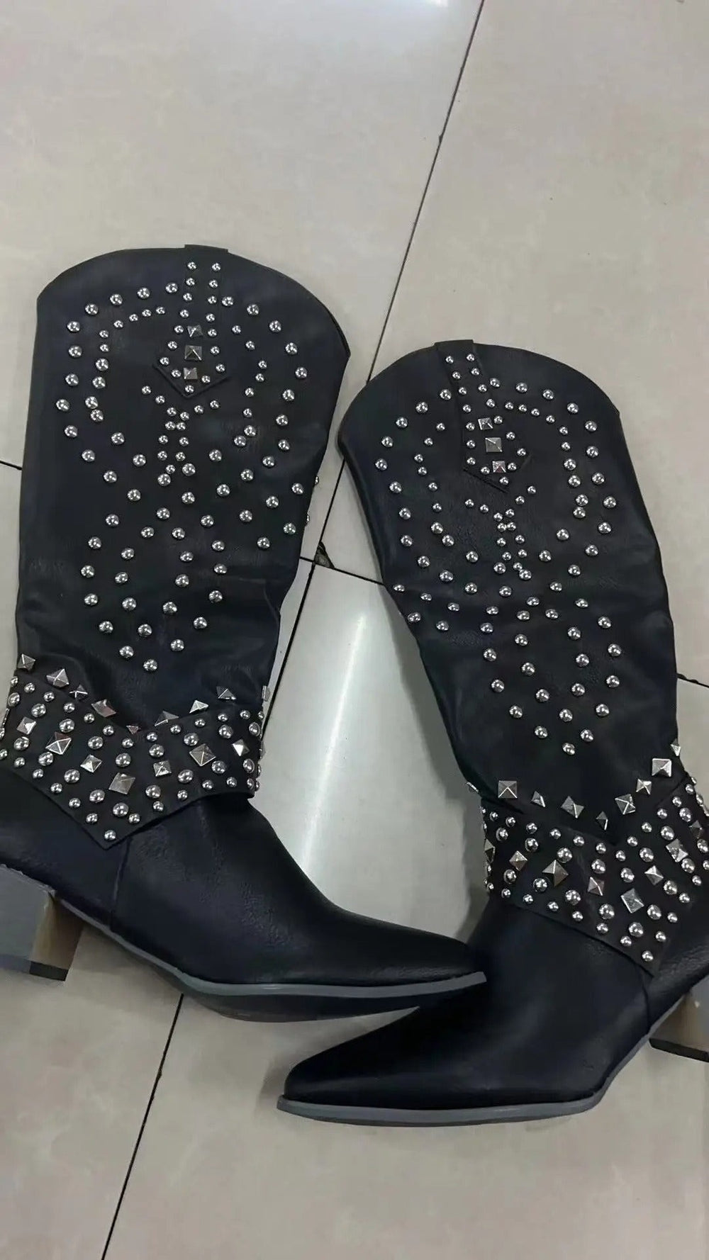 Black studded knee-high cowboy boots featuring pointed toe and stacked heel
