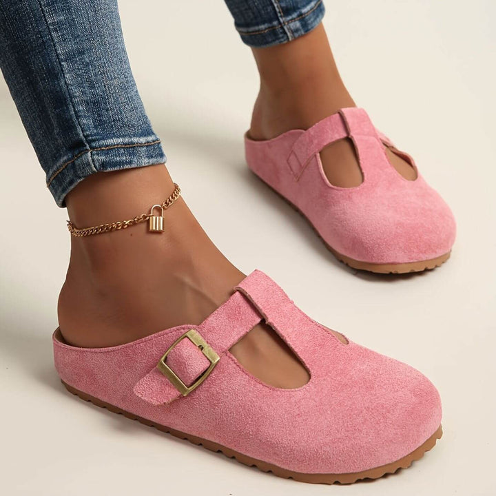 Pink suede T-strap buckle clogs styled with rolled denim jeans
