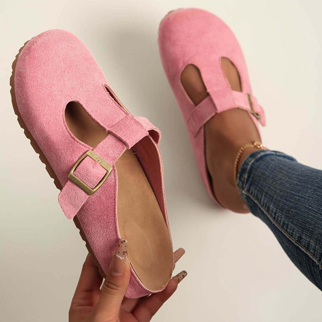 Close-up of pink suede clogs showing gold buckle and cushioned footbed