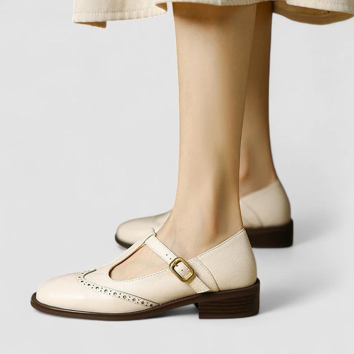 Cream leather T-strap Mary Jane shoes with brogue wingtip detailing and buckle