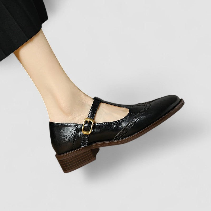 Black leather Mary Jane shoe with gold buckle and brogue wingtip pattern