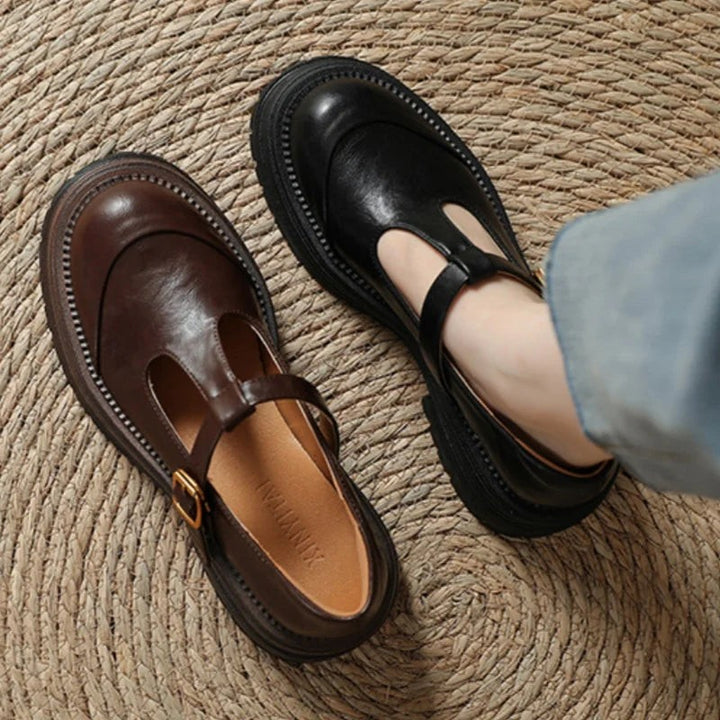 Brown and black leather Mary Jane shoes paired together on woven mat