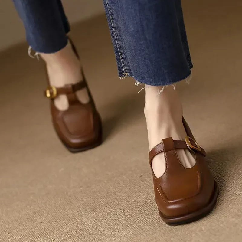 Brown T-strap Mary Jane shoes shown from behind with denim pants
