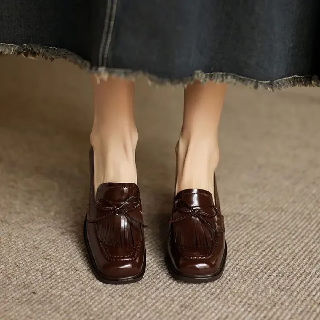 Front view of brown patent tassel loafer pumps on feet